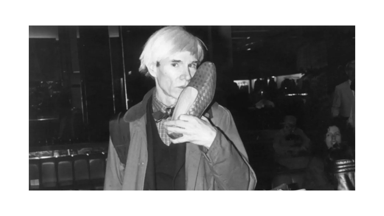 Andy Wahrol segurando um sapato da marca italiana Bottega Veneta que ele era obcecado.