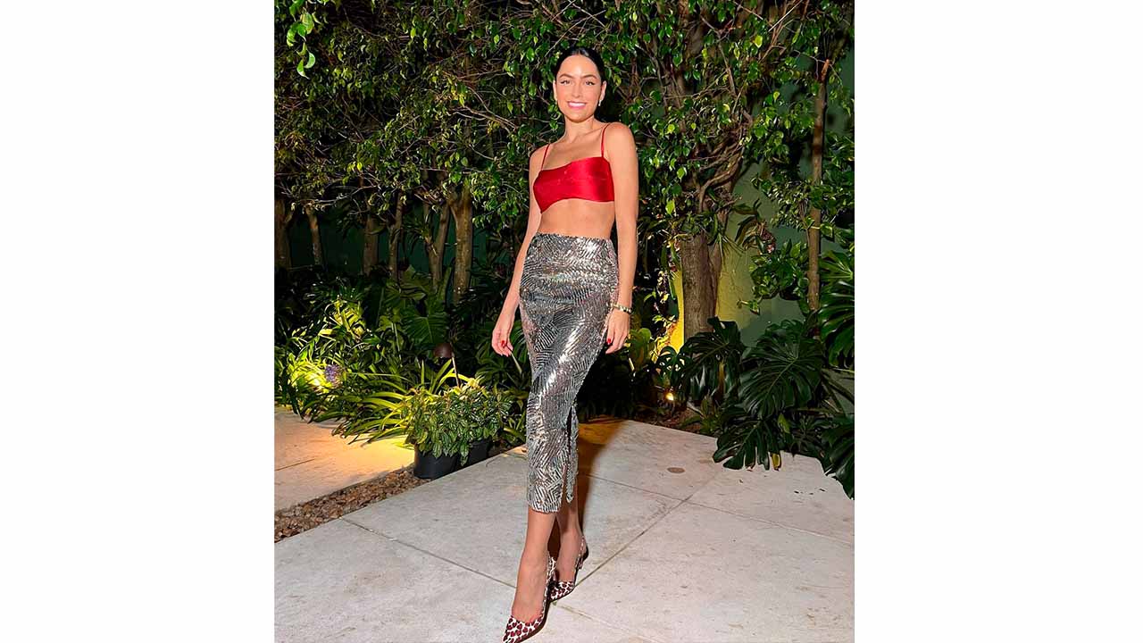 Foto de mulher usando saia com brilho e top de cetim compondo um look night luxe.