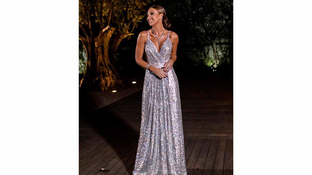 Foto de muher usando vestido brilhante que faz parte da tendência night luxe.