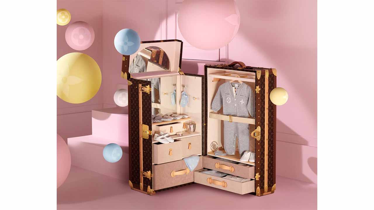 Foto com baú da Louis Vuitton com roupas da sua primeira linha para bebês.