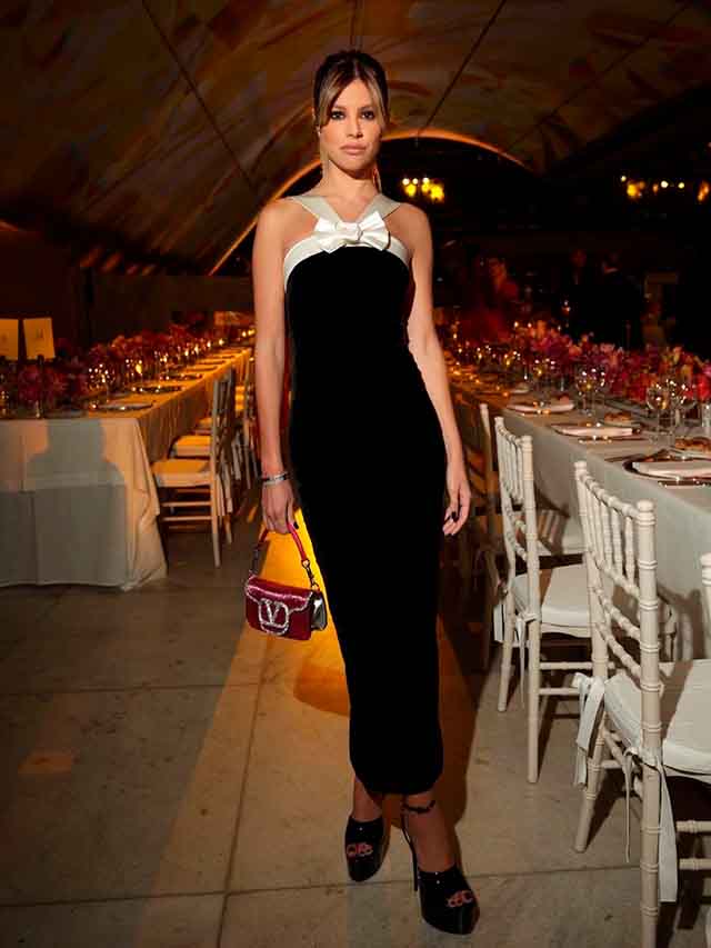 Mulher usando vestido de festa e bolsa pequena com  brilho.