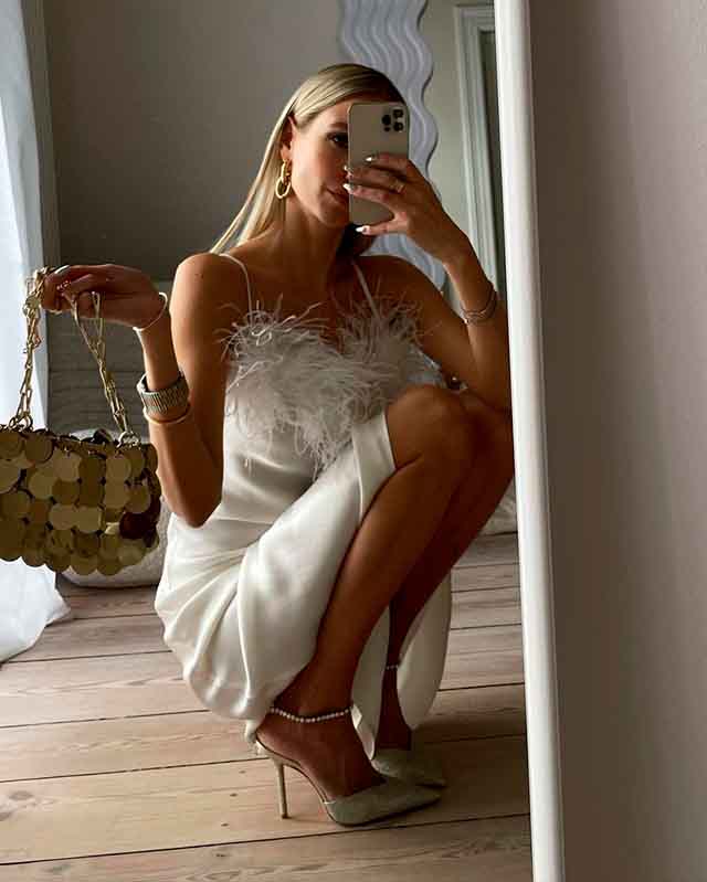 Mulher usando bolsa Paco Rabanne com vestido.