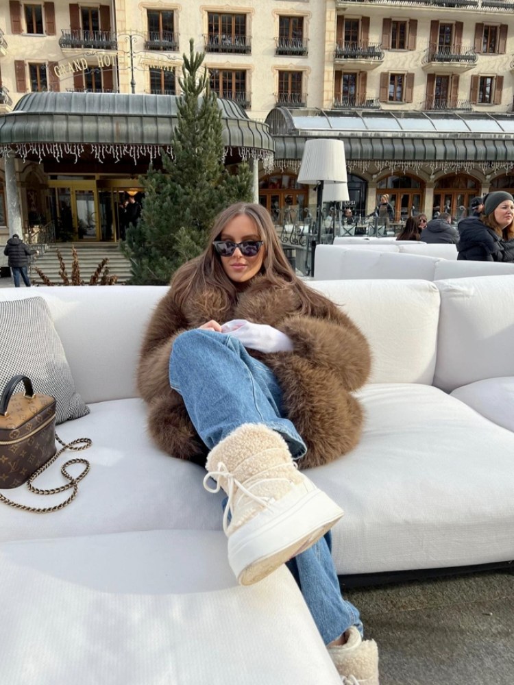 Mulher usando roupa de inverno com casaco de pelo, calça jeans e bota