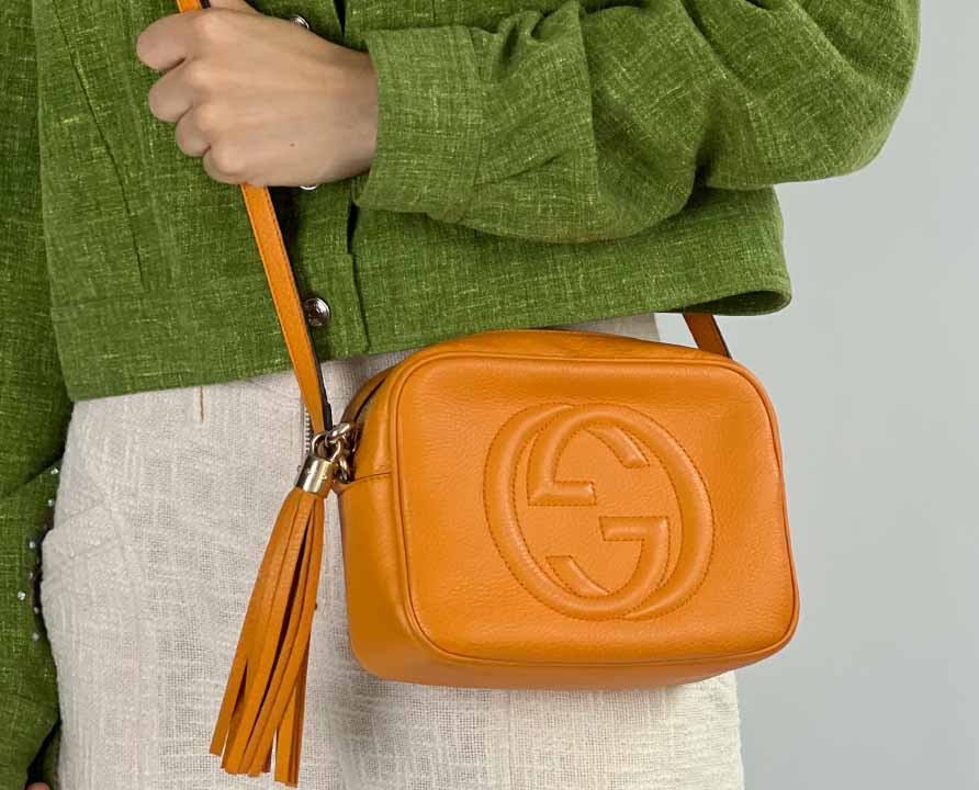 Foto de mulher usando uma das bolsas crossbody da Gucci, modelo Soho.