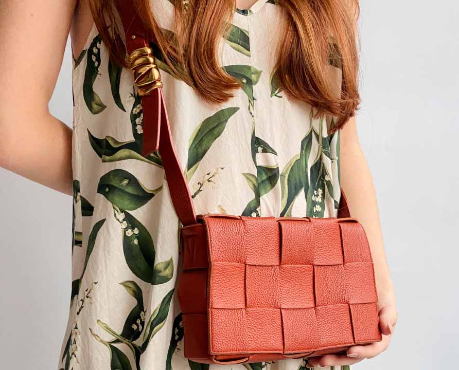 Foto de mulher usando uma das bolsas crossbody da Bottega Veneta, modelo cassete.