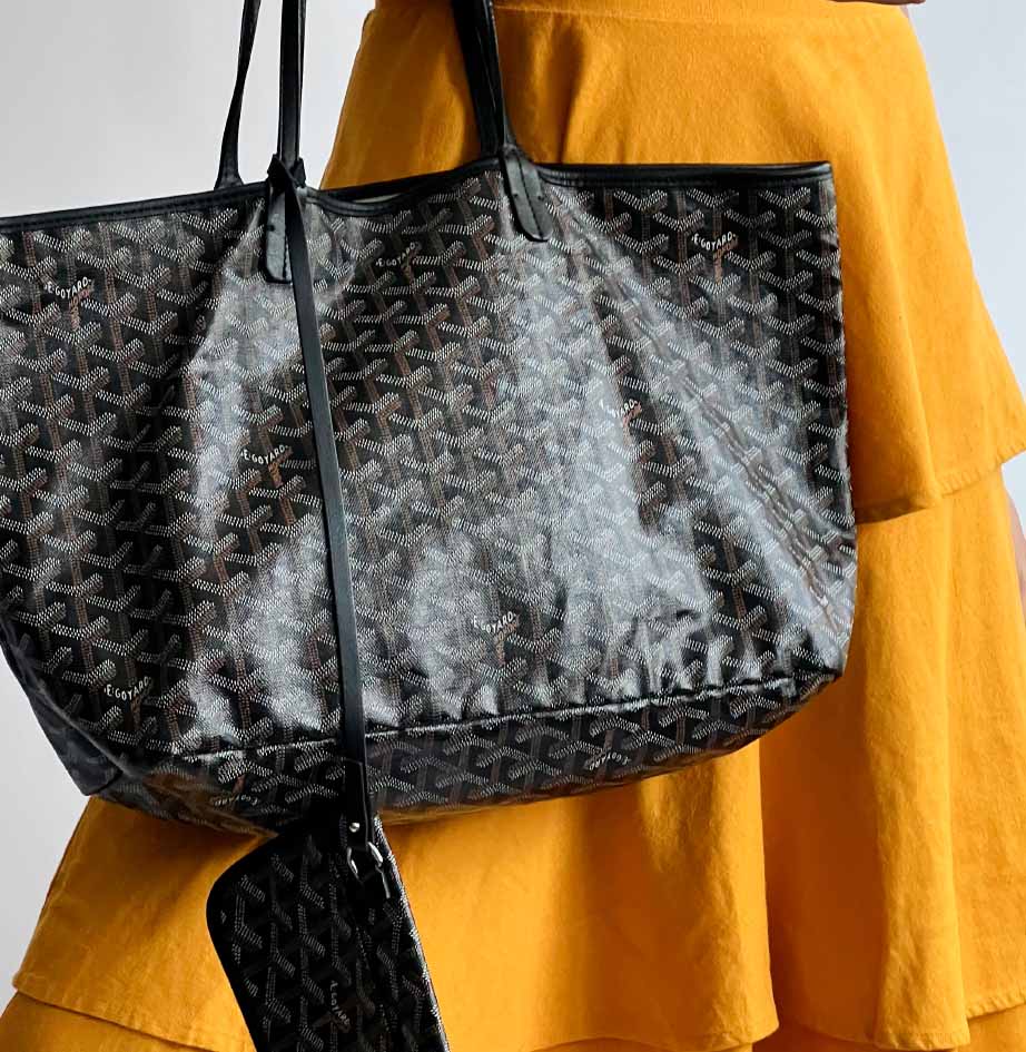 Foto de mulher carregando bolsa Goyard, modelo sacola perfeito para usar na universidade.