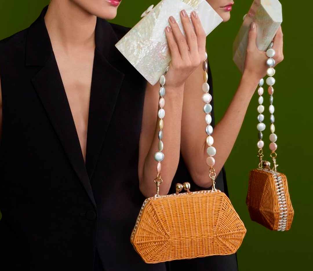 Foto de mulher carregando clutch de palha.