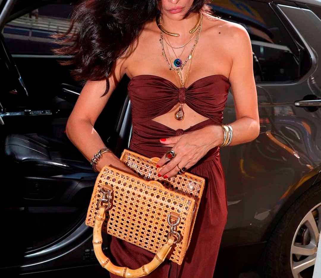 Foto de mulher usando bolsa de palha retangular na cidade.