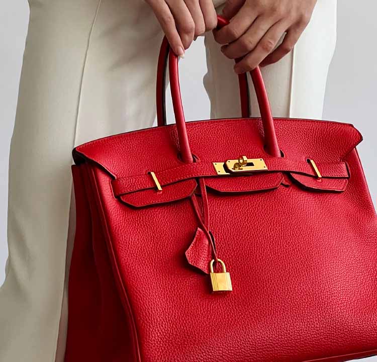 Foto de uma mulher segurando uma das bolsas tote mais desejadas da moda: Bolsa Birkin da hermès.