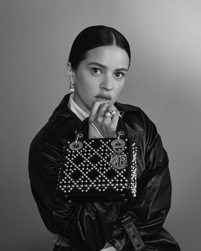 Foto da cantora Rosália segurando uma bolsa Lady Dior, a cantora é embaixadora da marca que contribue para a fama da Dior.