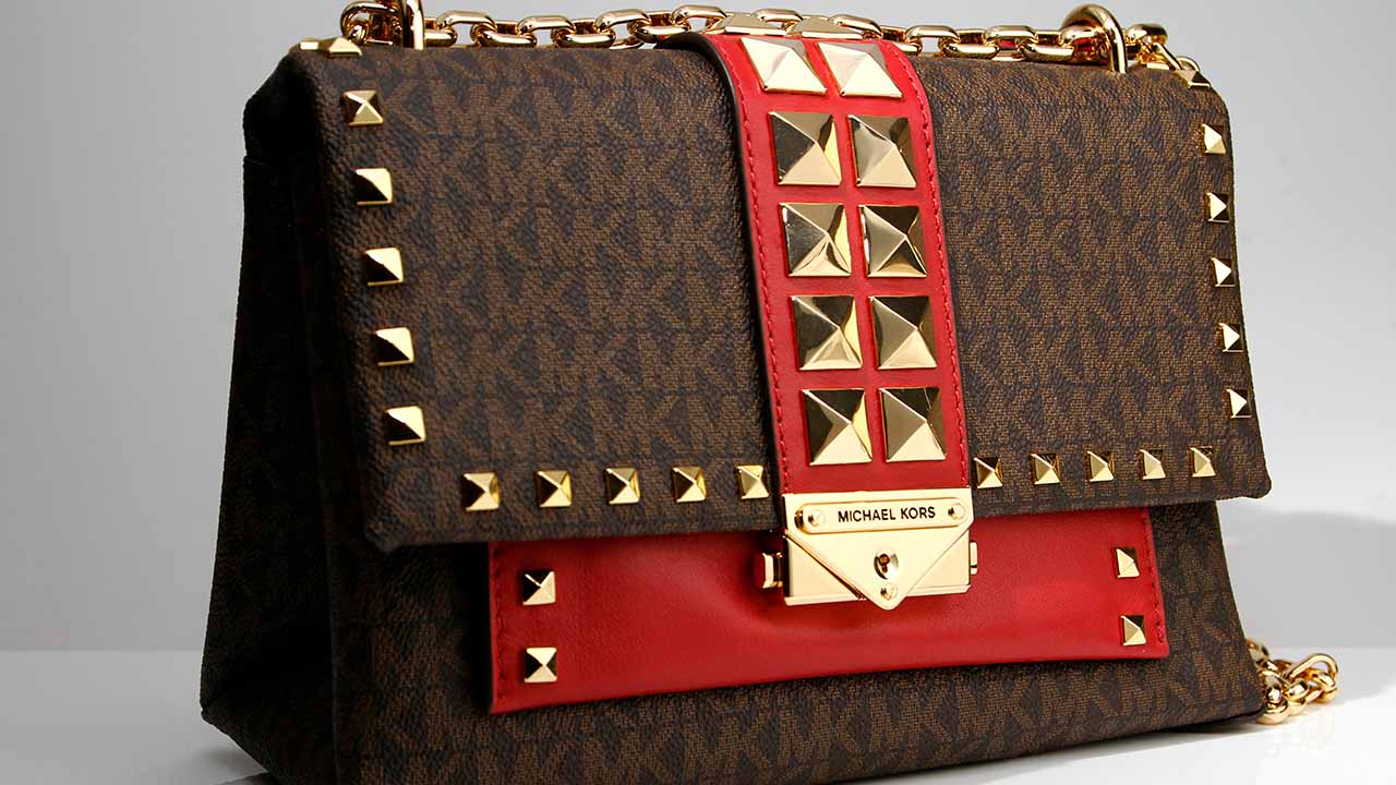 Foto de bolsa Michael Kors feita de couro com ferragens douradas.