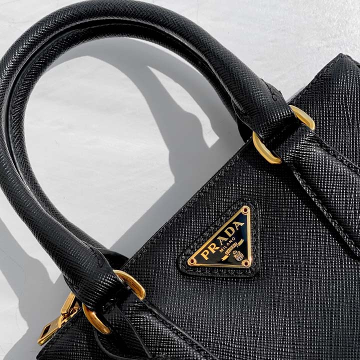 Foto de bolsa galleria Prada com zoom no famoso triângulo invertido da maison.