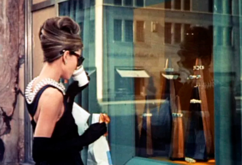 Foto da cena do filme Bonequinha de Luxo com Audrey Hepburn tomando café em frente a loja da Tiffany, que deu origem ao Blue Box Café.
