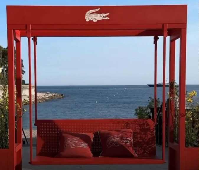 Foto do balanço vermelho com mar ao fundo do Café Lacoste instalado na  praia privada Le Méridien Beach Plaza.