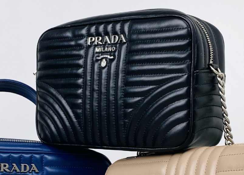 Foto de uma camera bag da Prada, modelo compacto com alça longa.
