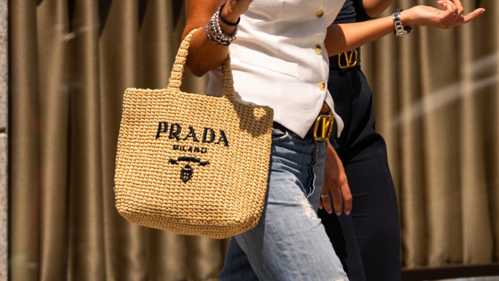 Foto de um look de verão com uma bolsa de ráfia da Prada.