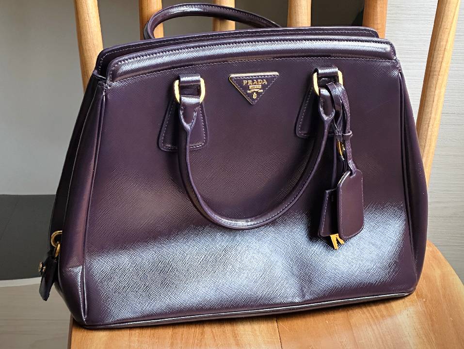 Foto de uma bolsa Prada com verniz em cor escura perfeita para sair à noite.