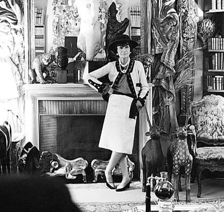 Coco Chanel usando terninho bicolor preto e branco com colares de pérolas, ícone da moda francesa e criadora do estilo clássico Chanel