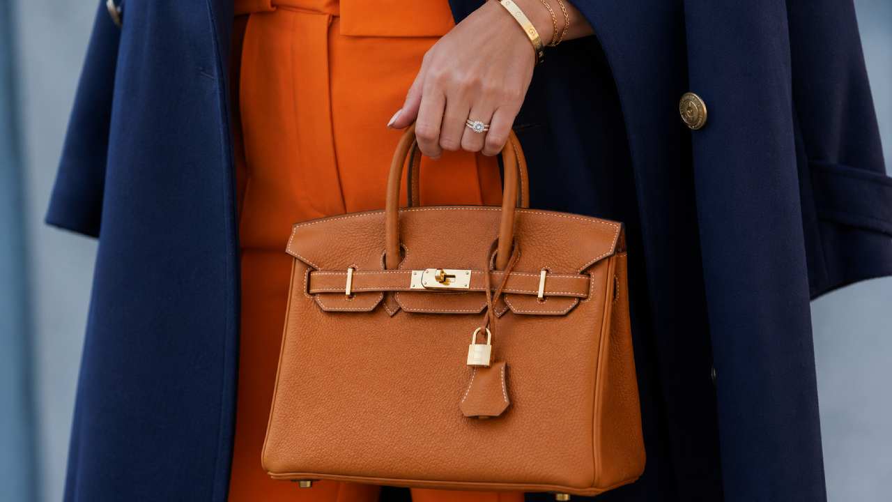 bolsa Birkin Hermès bege caramelo sobre fundo neutro, vista frontal com fechos dourados