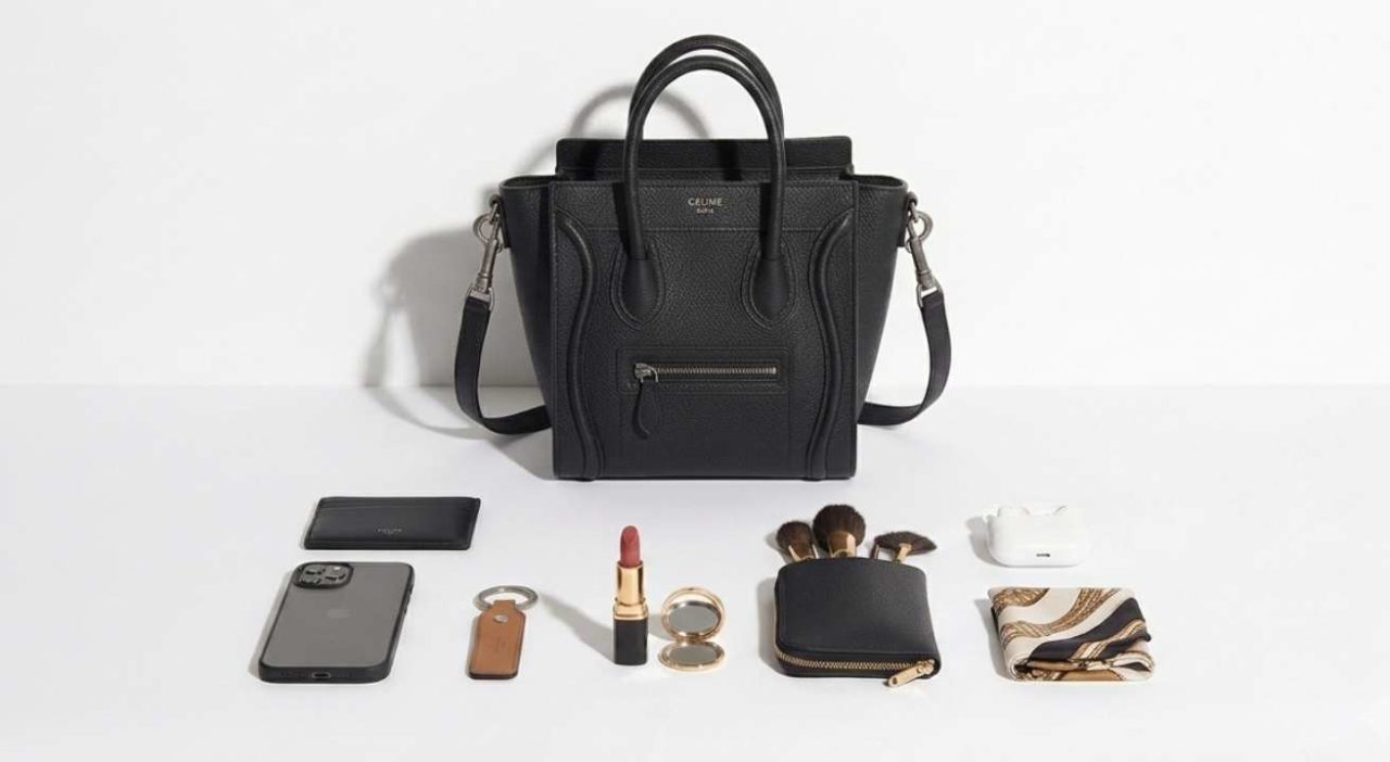 Bolsa Celine Luggage Nano com celular, carteira, chaves, óculos de sol e outros itens essenciais organizados ao redor para demonstrar sua capacidade.