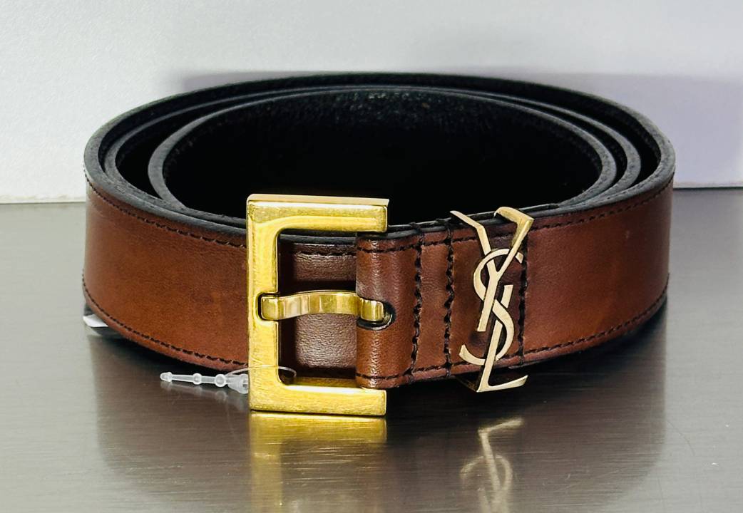 Cinto Saint Laurent Cassandre feminino em couro com fivela dourada YSL, acessório de luxo ideal para presentear no Dia dos Namorados 2026.