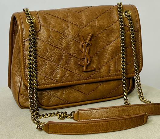 Bolsa Saint Laurent Niki em couro matelassado com corrente metálica e logo YSL, uma das bolsas femininas de luxo mais procuradas da marca.