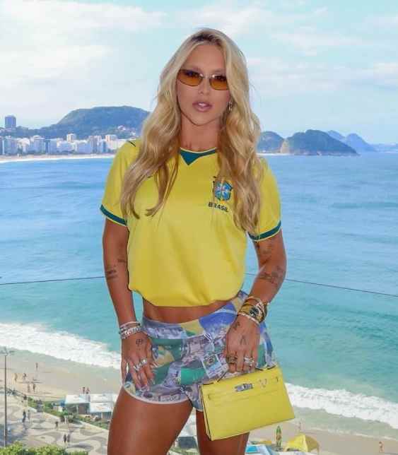 Virginia Fonseca usando bolsa de luxo amarela inspirada nas cores da Seleção Brasileira para a Copa do Mundo 2026, com look fashionista e tendência entre celebridades e WAGs do futebol.